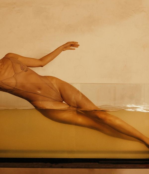Woman maintaining a difficult balance pose in a minimalist studio.